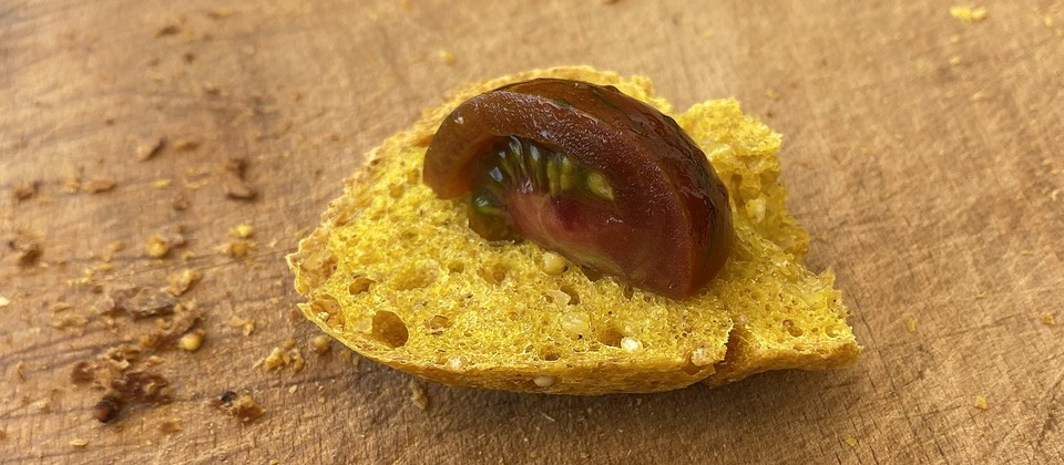 Dark tomato on a piece of my bright yellow experimental turmeric bread