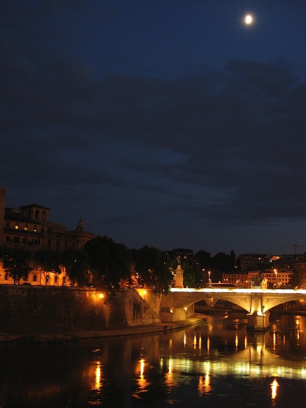 Fullish moon shing over Rome at night with the lights of the Ponte Vittorio Emanuele II reflected in the Tiber