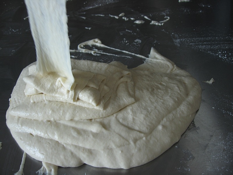 Sticky, liquid dough being poured out onto the counter for wrestling